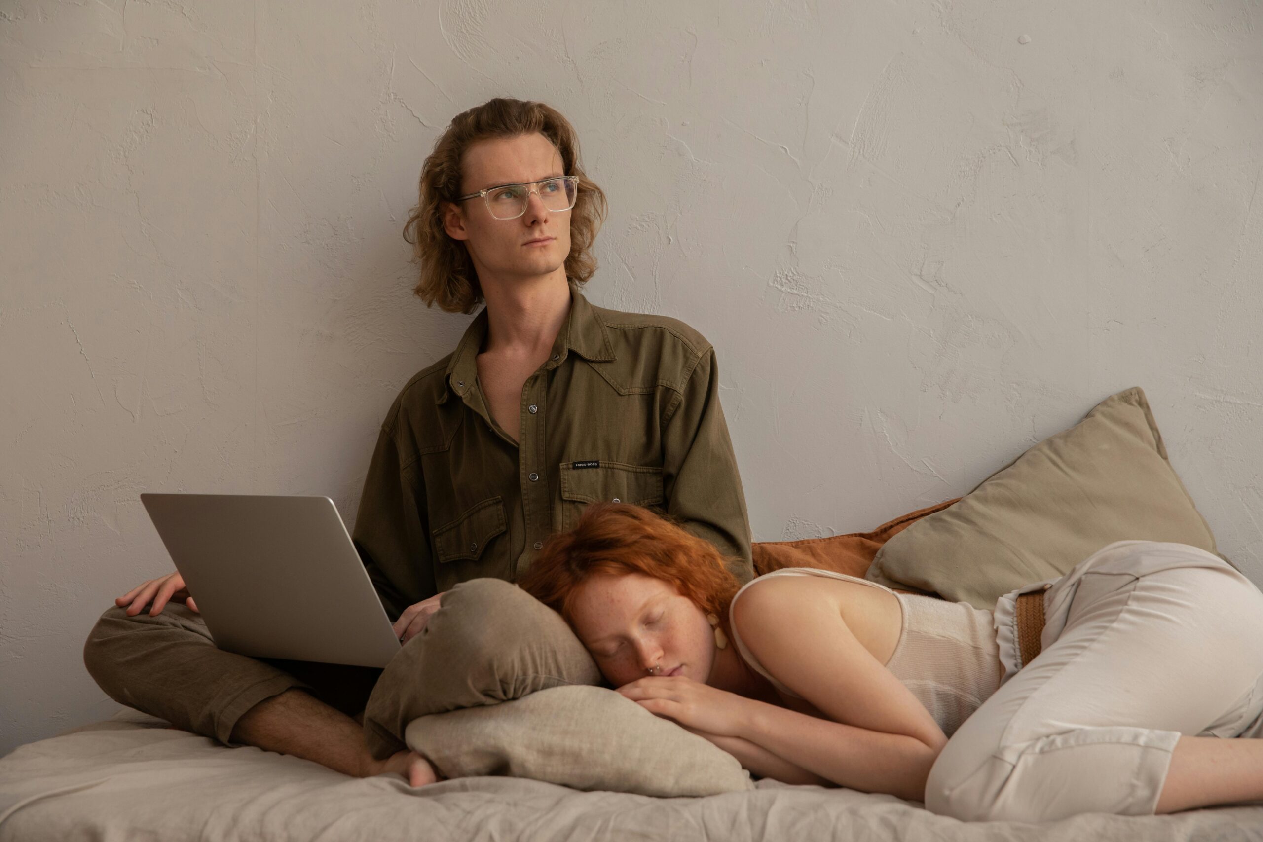 Man with laptop and woman relaxing on bed, perfect for remote work and lifestyle themes.