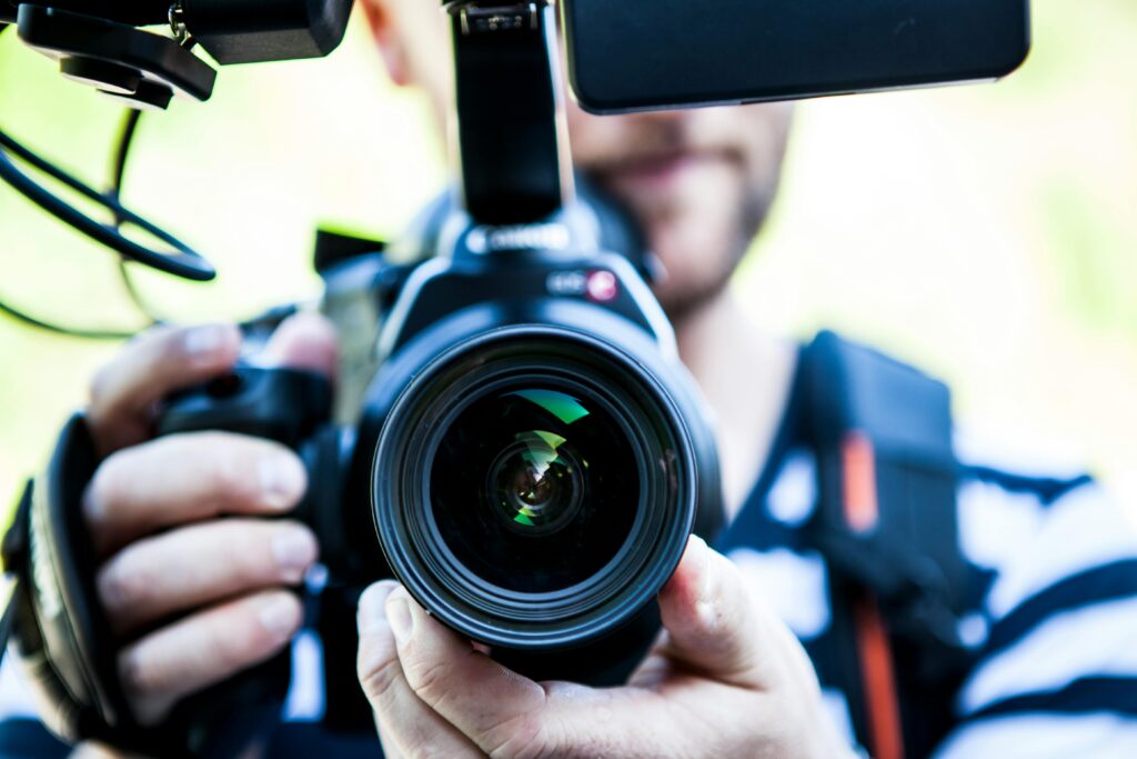 A close-up shot of a cameraman filming, focusing on the camera lens and equipment. To show webbolt money stream by YouTube.